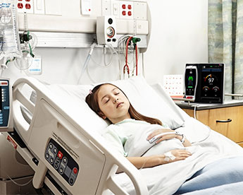 Paziente in un letto d'ospedale che indossa un sensore Masimo con dispositivo Root sullo sfondo.