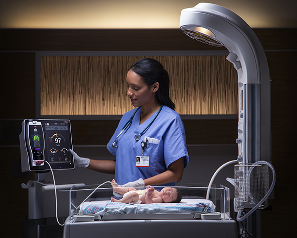 Medico che controlla il monitor Root collegato a un bambino in una ICU neonatale