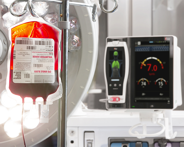 Consegna di sacca di sangue EV vicino a un dispositivo di monitoraggio al posto letto.