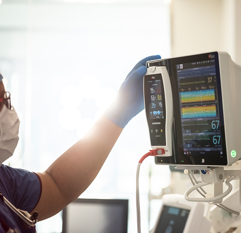 Operatore sanitario che usa un sistema di monitoraggio dei pazienti Masimo per vedere le tendenze avanzate dei segni vitali.